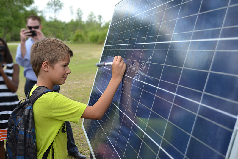 A kid signs one of the first solar panels installed at the City's solar farm.