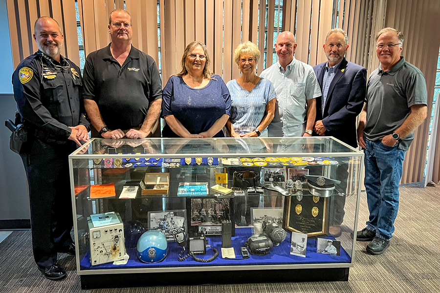 People standing around a new display case featuring historical items