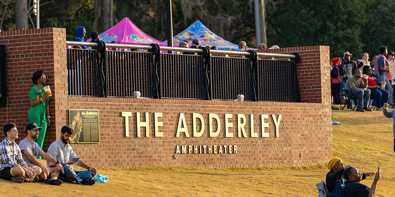 People enjoying park space in front of the Adderley Amphitheater sign