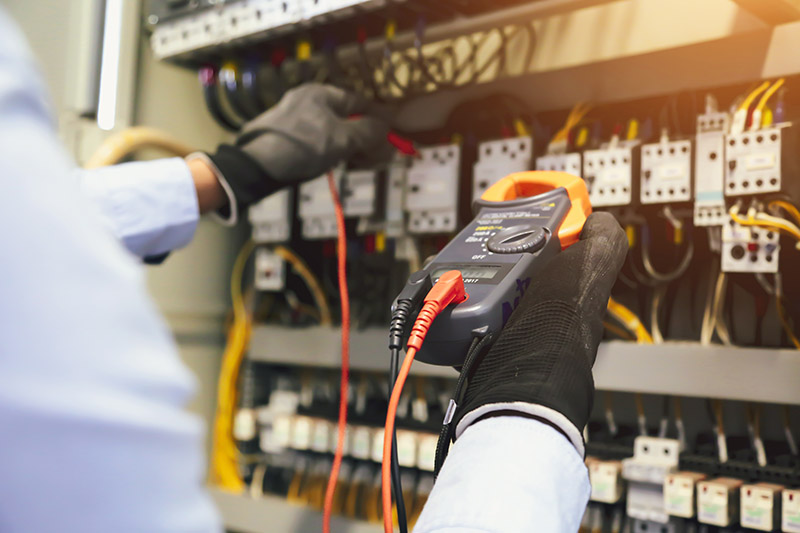 an electrician working on an electrical panel with a meter